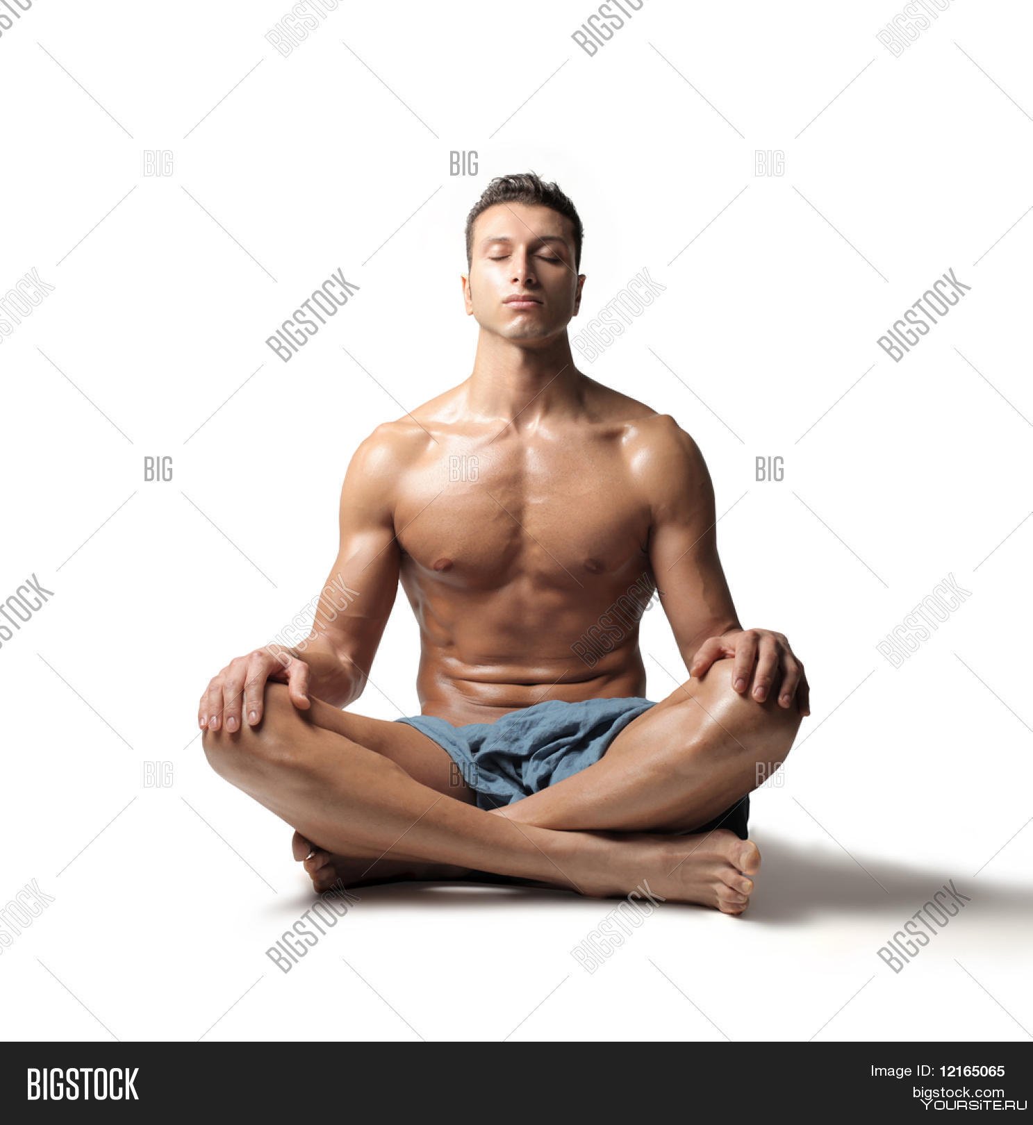 Мужчина сидит раздвинув ноги. Мужчина в позе лотоса. Мужчина медитирует. Накаченный парень сидит.
