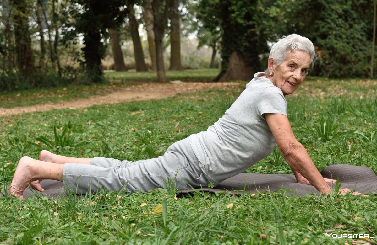 Пожилая женщина йога на траве