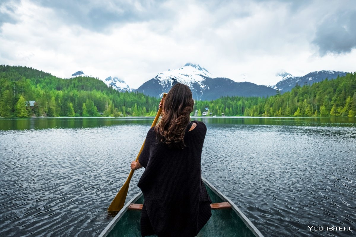 Девушка в лодке на озере со спины