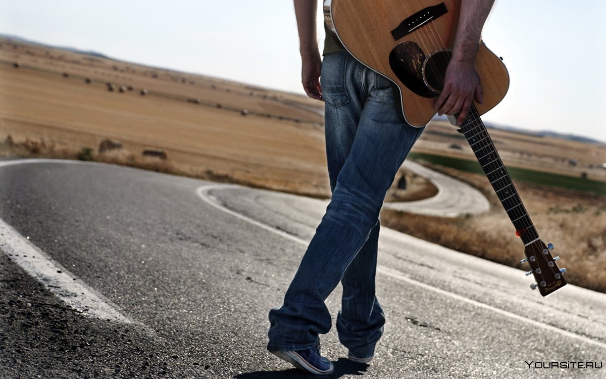 Человек с гитарой на дороге
