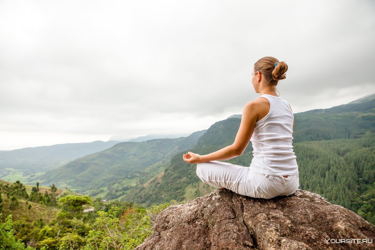 Девушка медитирует в горах
