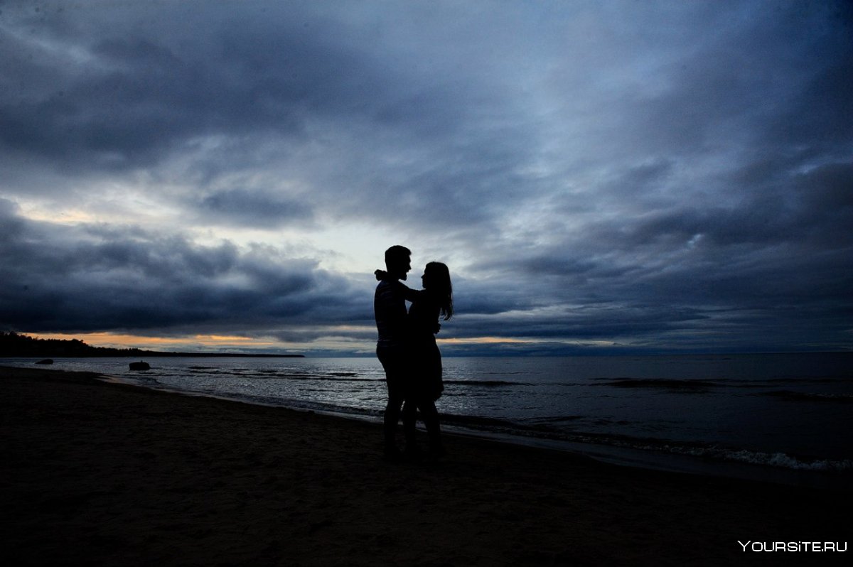 Влюбленная пара на берегу моря на закате