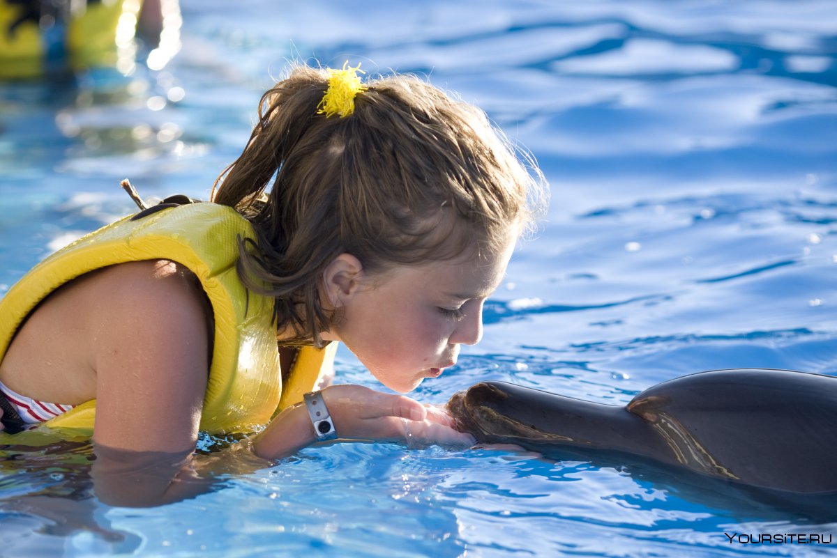 Ребенок плавает с дельфином
