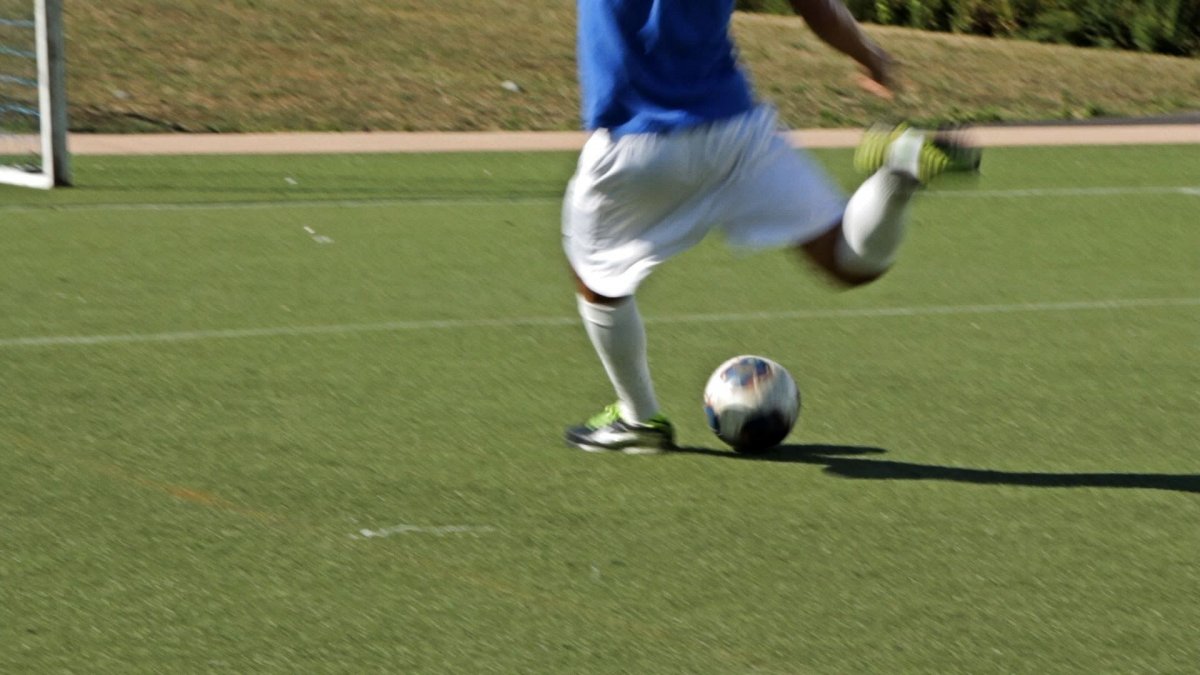 Футболист пинает мяч