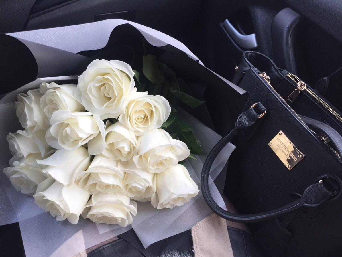 Красивый букет белых роз в машине ночью