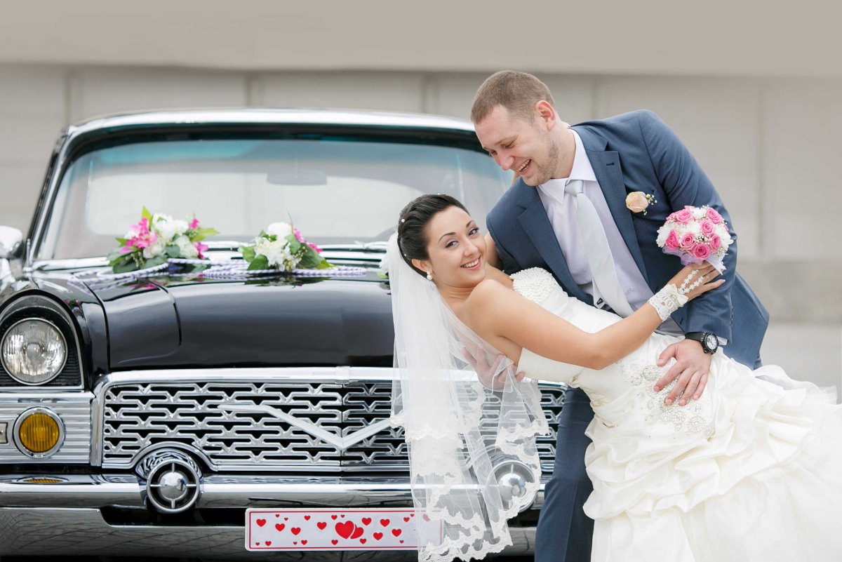 Жених и невеста сидят на лимузине